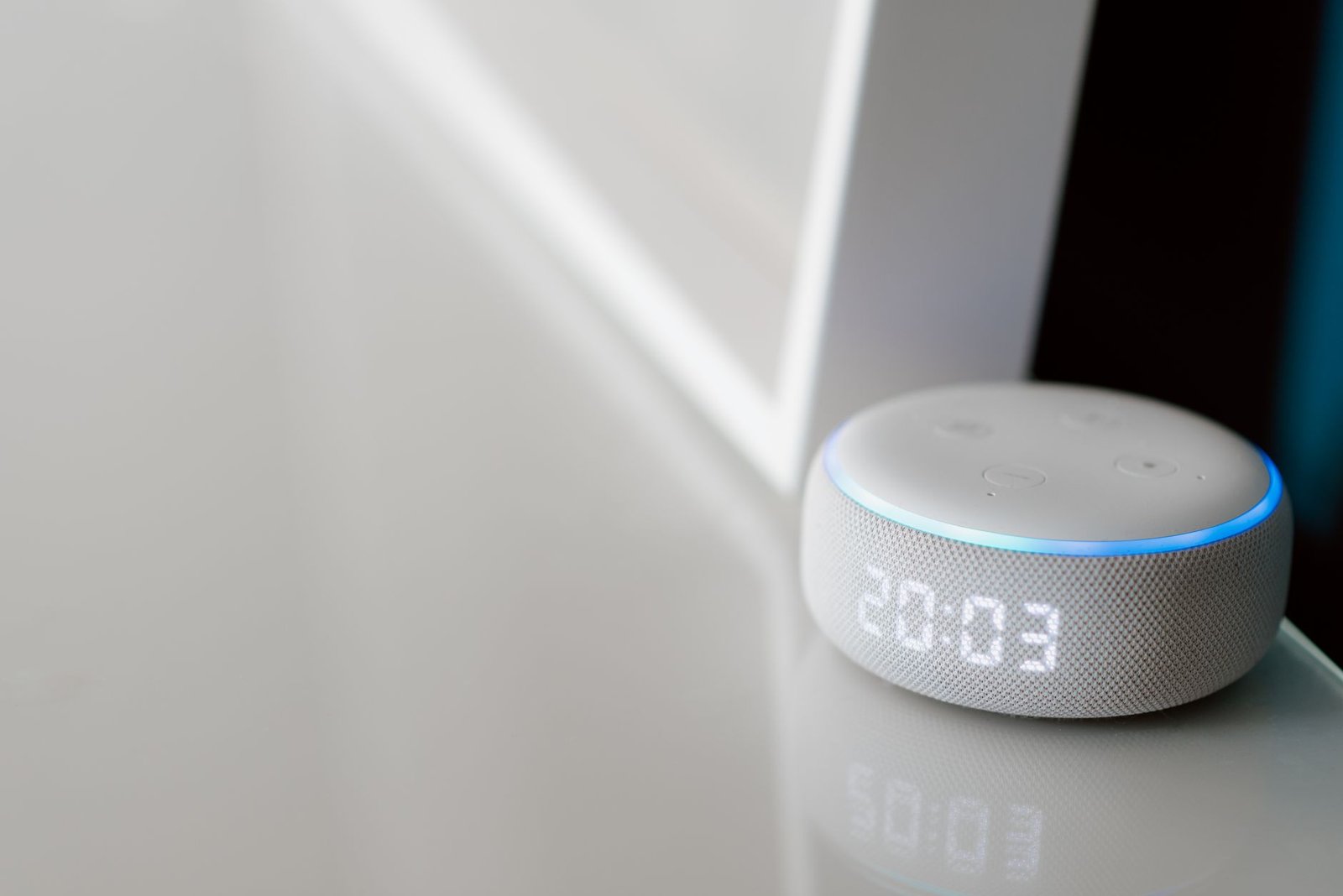 The Internet of Things - Close-up of a smart speaker with a digital clock display on a minimalist surface.