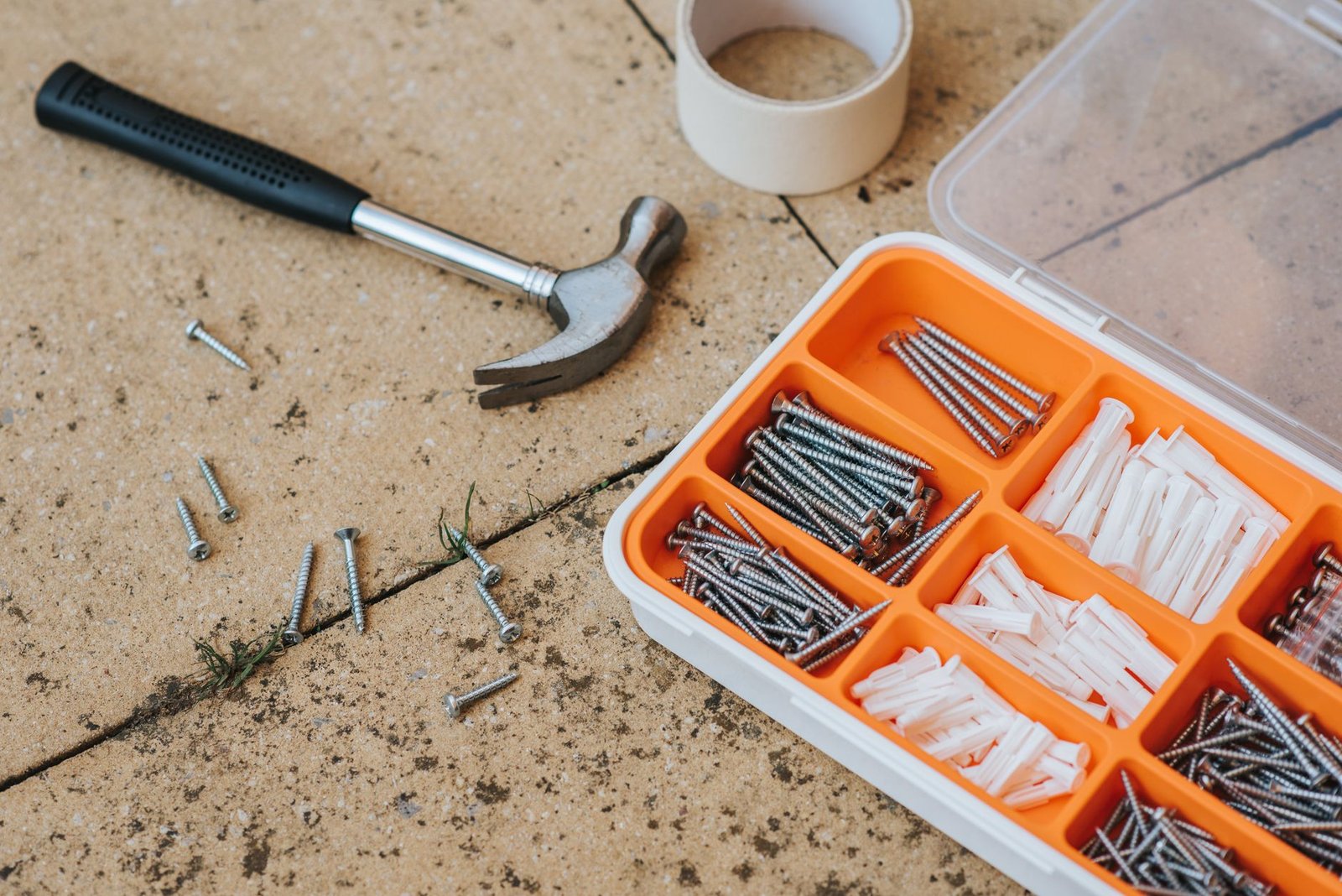 DIY Home Improvement and Maintenance Diploma - Top view of assorted repair instruments and screws in box near hammer and scotch tape on dirty tile in soft daylight