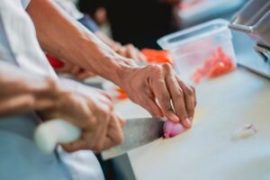 HACCP Certification - Close-up of a chef slicing onion in a kitchen setting, emphasizing food preparation.