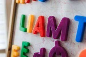 Teaching Phonics Level 2 Certification - Close-up of vibrant magnetic letters spelling 'LIAM' on a whiteboard for educational purposes.