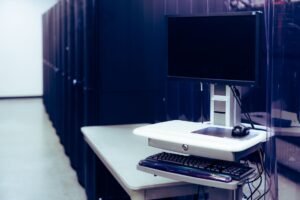 Computers and Internet for Beginners Certification - Contemporary computer with black screen placed on stand near row of server steel racks in data center