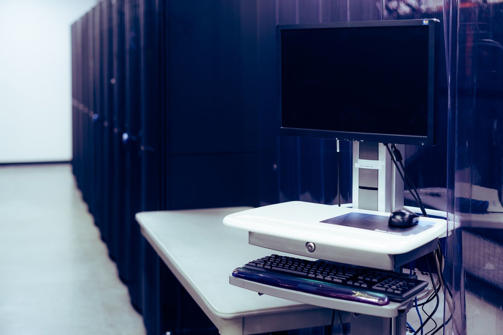 Computers and Internet for Beginners Certification - Contemporary computer with black screen placed on stand near row of server steel racks in data center