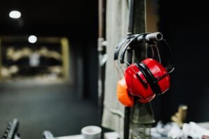 Noise and Hearing Protection Certification - Red ear muffs hanging at an indoor shooting range, offering essential safety gear.
