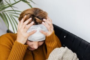 Concussion Awareness Certification - Woman with head injury holding her head in pain indoors.