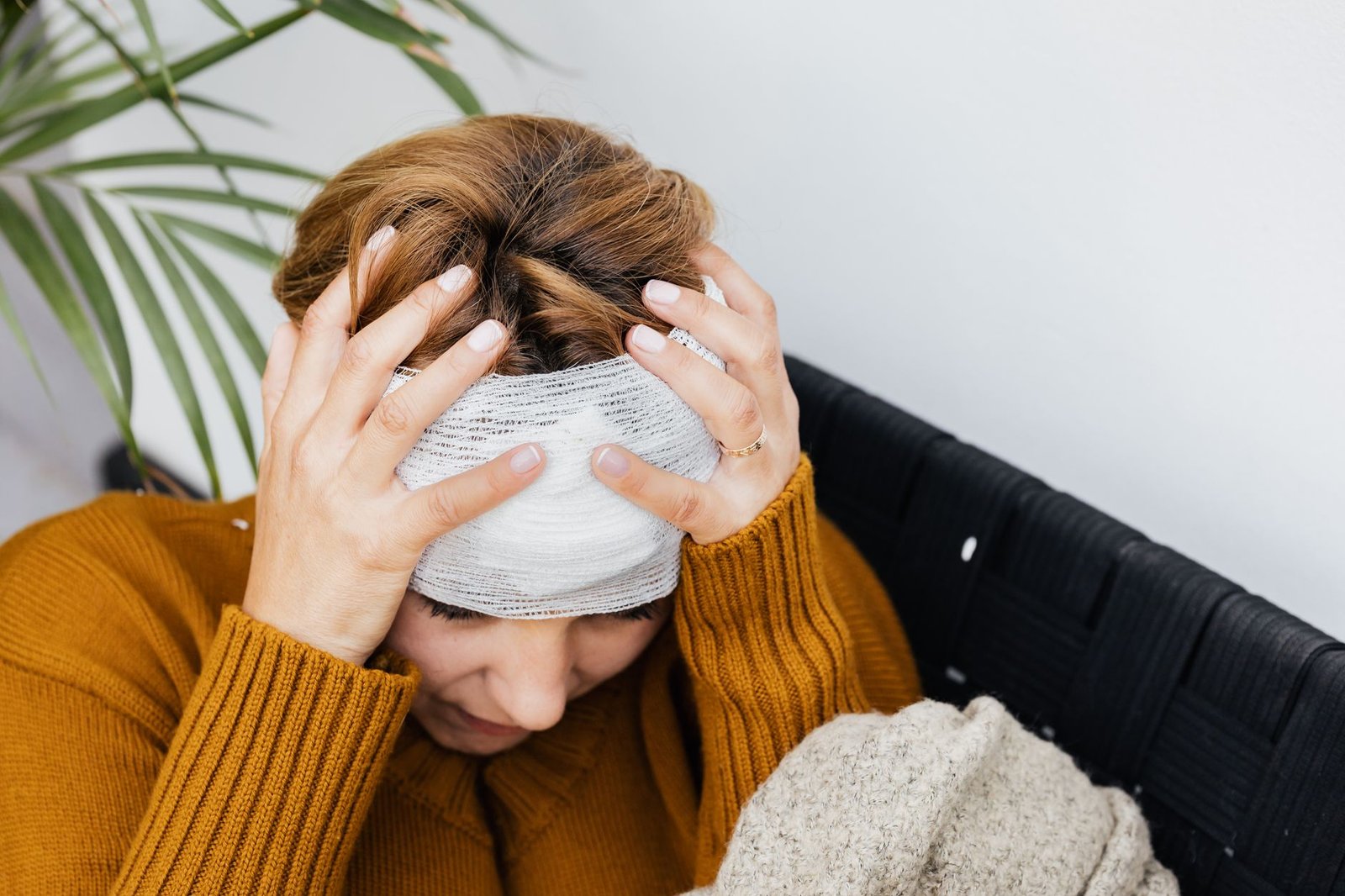 Concussion Awareness Certification - Woman with head injury holding her head in pain indoors.