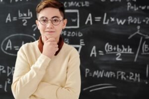 The Basics of Critical Thinking Certification - Smart student in glasses posing confidently in front of a blackboard full of mathematical equations.