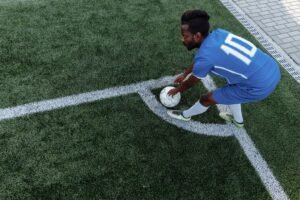 Training for Sport Certification - A soccer player in a blue jersey prepares to kick the ball from the corner on an artificial turf field.