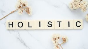 Introduction to Holistic Health Certification - Flat lay of 'holistic' spelled in letter tiles on marble with dried flowers.
