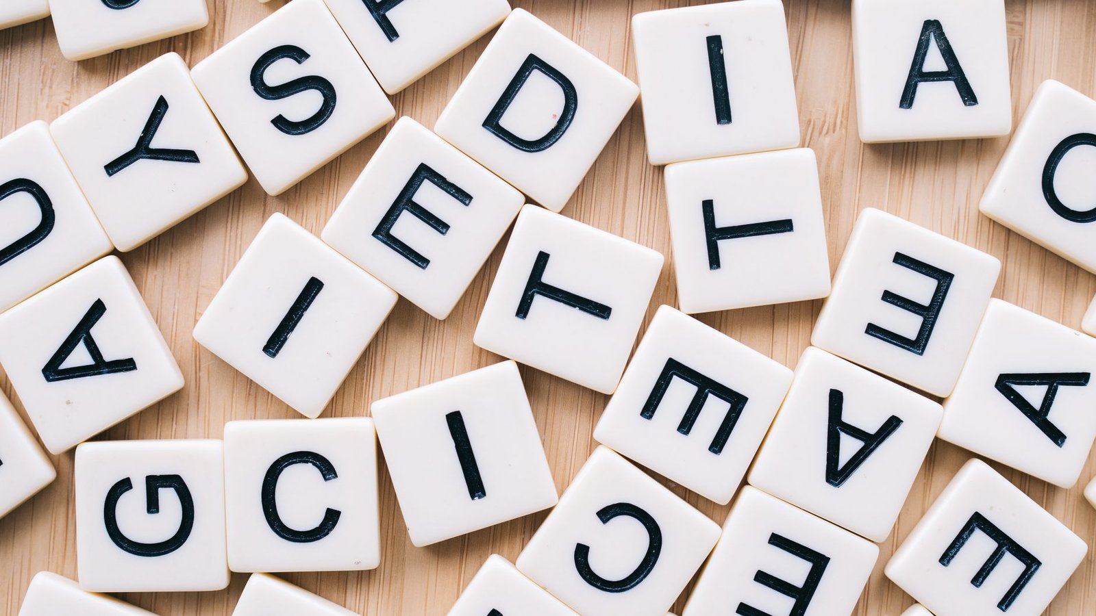 Dyslexia Awareness Certification - Closeup of scattered scrabble tiles against a wooden background, ideal for word games and learning themes.