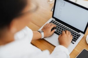 Email Etiquette - High angle shot of a person typing on a laptop, focused on hands and keyboard.