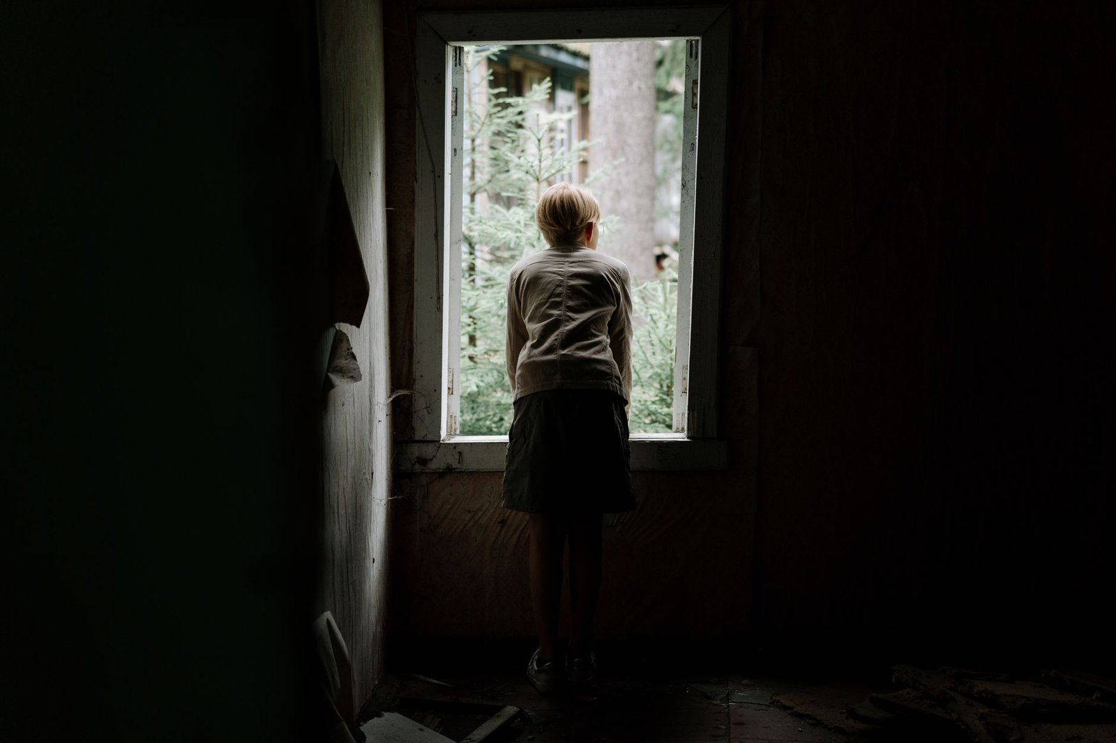 Child Sexual Exploitation Awareness Certification - A young child curiously looks through a window of an abandoned building into the greenery outside.