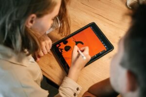Adobe Illustrator Certification Level 1 - Two people creating a Halloween-themed digital illustration using a tablet and stylus.