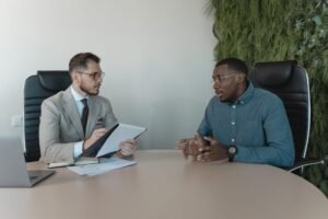 Interviewing Skills Certification - Two businessmen engaged in a discussion during a job interview in a contemporary office environment.