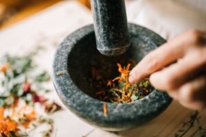 How To Use Garden Herbs Certification - A hand crushes vibrant herbs in a stone mortar, blending natural ingredients.