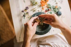Herbal Health Certification - Close-up of hands mixing dried herbs with a mortar and pestle for herbal medicine preparation.