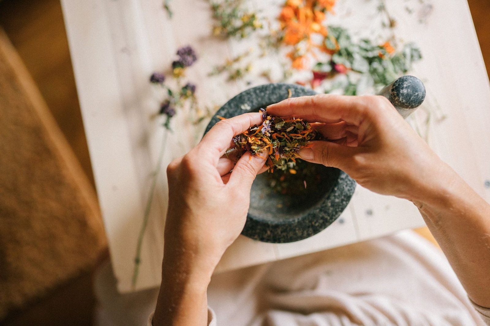 Herbal Health Certification - Close-up of hands mixing dried herbs with a mortar and pestle for herbal medicine preparation.
