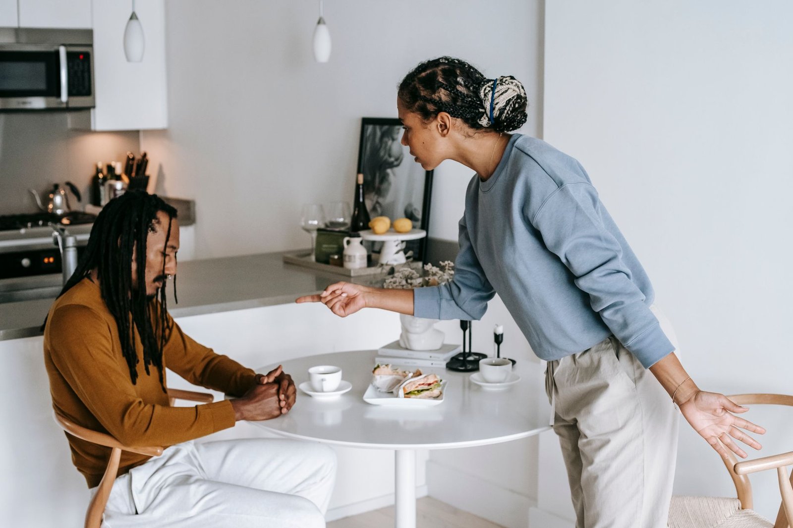 Handling Conflict in Low-Value Relationships Certification - Young black woman blaming ethnic depressed boyfriend sitting at table in living room at home