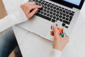 Retail Banking Certification - Close-up of a person using a laptop and holding a credit card for online shopping.