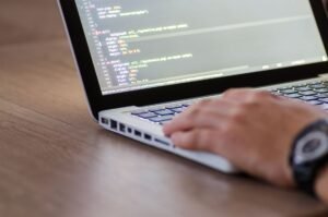 Neuro-Linguistic Programming Certification - Person coding on a laptop with HTML code on screen, showcasing development work.