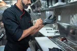 Food Safety Level 3 Certification - Chef putting on gloves in a professional kitchen setting, emphasizing hygiene and readiness.