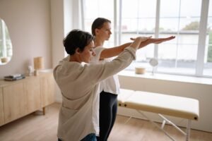 Professional Body Healing Coach Certificate - A therapist helps a client with therapeutic exercises in a wellness clinic.