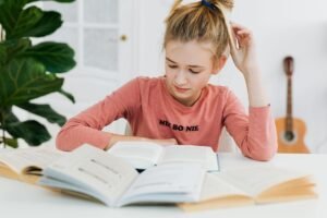 Boost Your Concentration Certification - Teen girl focusing on studying with open books at a bright indoor desk.