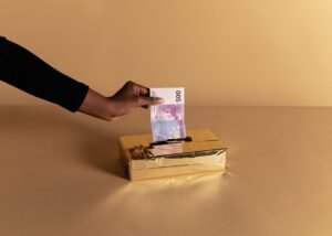 Global Anti-bribery and Corruption Certification - Euro banknote held by a hand against beige background, symbolizing bribery or gifting.