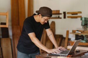 Create an Online Business Certification - Concentrated ethnic man in casual clothes and eyeglasses browsing netbook while working in creative workspace in daytime