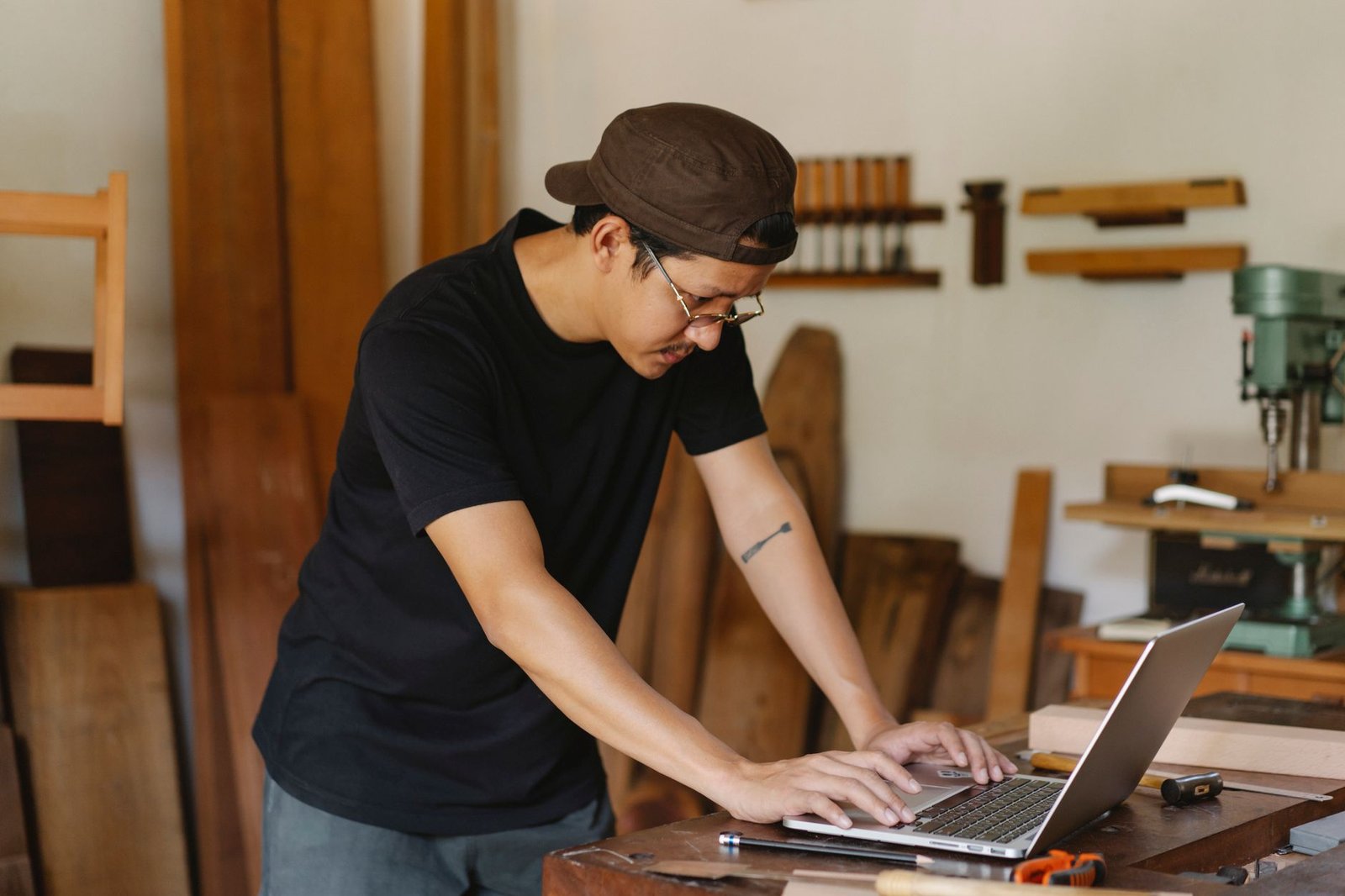 Create an Online Business Certification - Concentrated ethnic man in casual clothes and eyeglasses browsing netbook while working in creative workspace in daytime