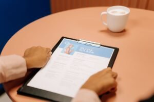 Interview Skills and CV Writing Certification - Close-up of hands holding resume during interview with coffee on table, highlighting workplace setting.