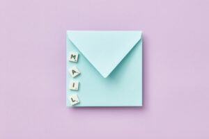 Microsoft Mail Merge Certification - Minimalist flat lay showing a blue envelope and 'MAIL' spelled with Scrabble tiles on a purple background.