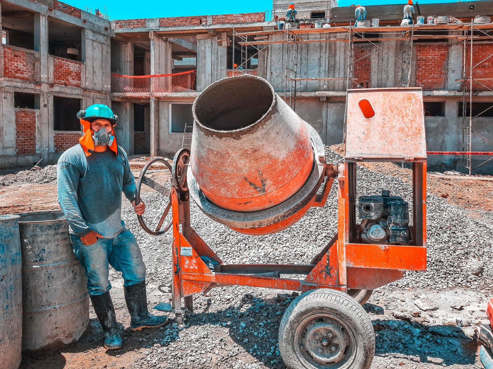 Construction Management Certification Level 1-3 - A construction worker operating a concrete mixer at an active building site, emphasizing safety gear.