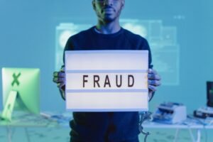 Identity Theft - A man holding a sign reading 'FRAUD' in a tech environment, highlighting cybersecurity concerns.
