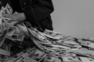The Human Element of Fraud Certification - A blur of hands moving through a pile of US dollar bills, captured in black and white.