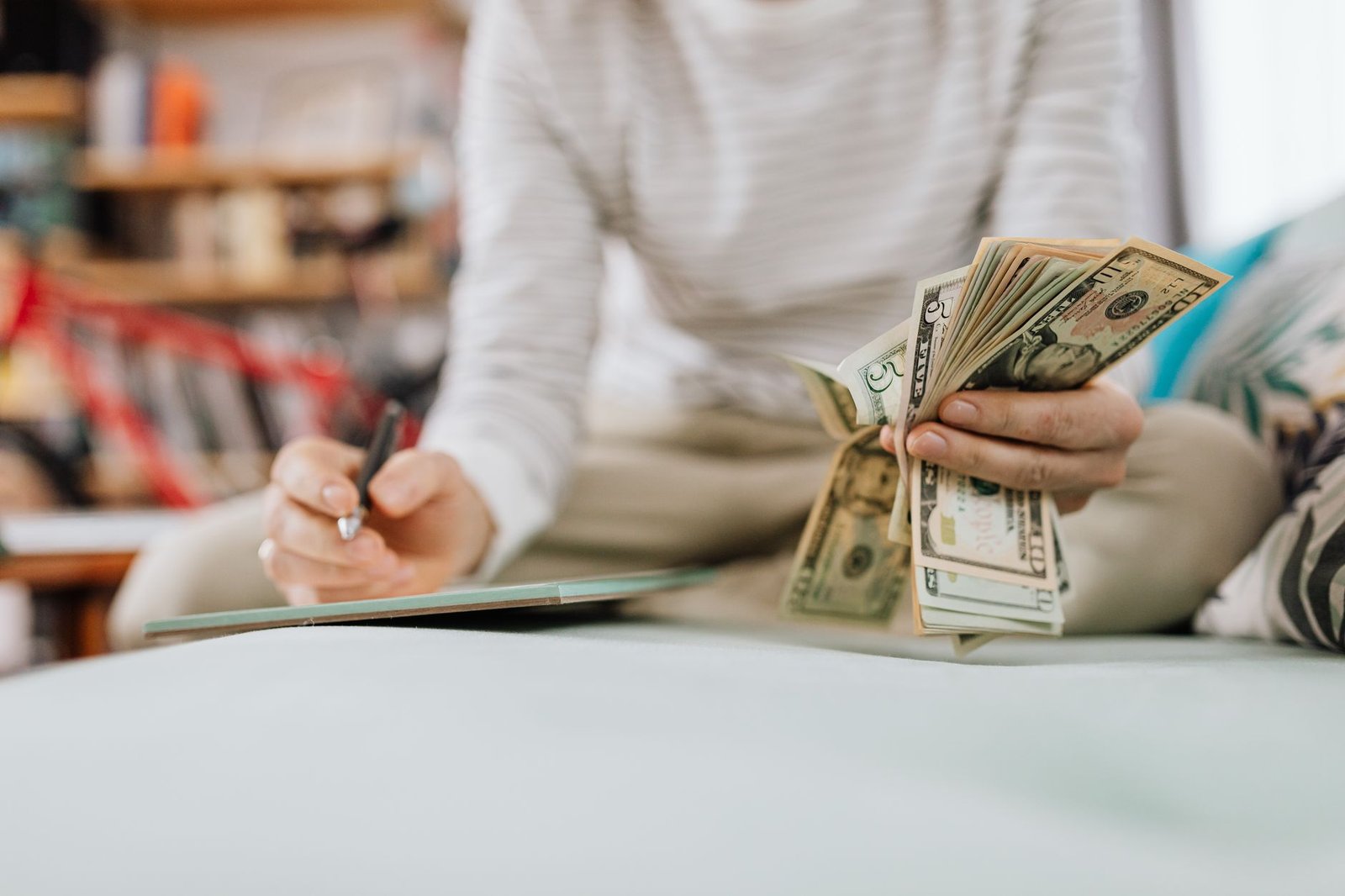 Personal Finance Certification - Individual counting money with pen in hand inside a cozy room setting.