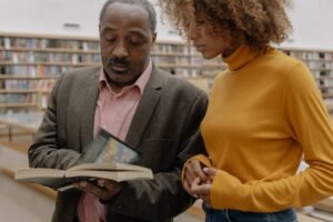 Teaching Adults to Read Certification - Two students studying together in a library, focusing on a book.