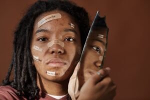 Self-harm Awareness Certification - A powerful portrait of a woman embracing imperfections with positive messages on her face, holding a broken mirror.