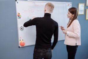 Teaching English to Speakers of Other Languages (TESOL) Certification - A student and teacher engage in an English lesson on a whiteboard. Indoor educational setting.