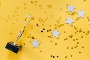 Extrinsic and Intrinsic Rewards Certification - Shiny golden trophy and stars on a vibrant yellow background, symbolizing success and victory.