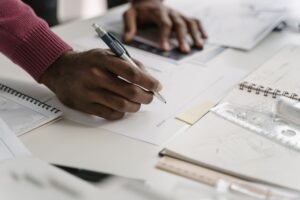 Foundation in Business Skills Certification - Close-up of architect drafting on blueprints in a modern office environment.