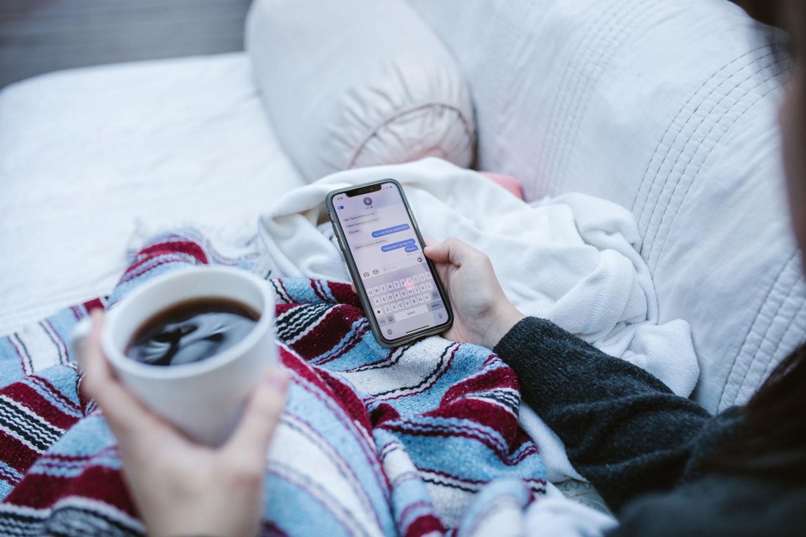 How to Handle Social Media Criticism Certification - Person relaxing indoors with coffee and smartphone, texting in a cozy setting.