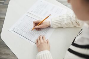 Myers–Briggs Theory and Test Certification - Close-up of a student filling out a multiple-choice exam in a quiet classroom setting.