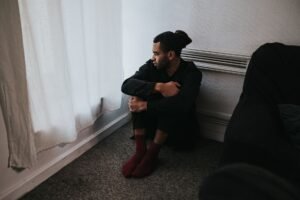 Borderline Personality Disorder Awareness Certification - A contemplative man sits in a corner of a dimly lit bedroom, reflecting deep emotions.