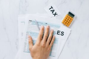 Introduction to Tax Accounting Certification - Close-up of a hand on tax form 1040 with a calculator on a desk.