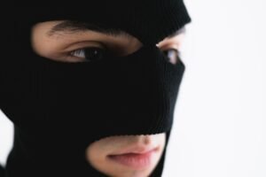 The Proceeds of Crime and Terrorism Acts Certification - Intense close-up portrait of a person wearing a black balaclava mask.