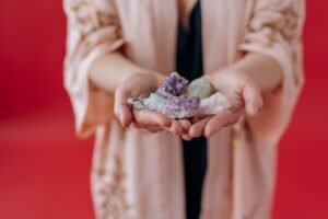 Animal Reiki Certificate - Elegant hands holding healing crystals against a vibrant red background.
