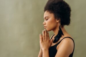 The Power of the Mind Certification - A young woman with afro hair practicing calming meditation indoors.