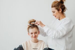 Hair for Parents Certificate - A mother styles her daughter's hair in a cozy indoor setting, showcasing family bonding.