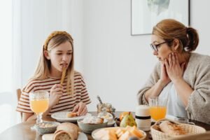 Understanding Dysphagia and Choking Certification - A mother and daughter enjoying a cozy breakfast together at home, featuring a variety of healthy foods.
