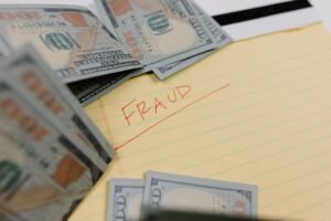 Fundamental Concepts of Fraud Certification - Close-up of US dollars and 'Fraud' written on yellow paper, representing financial scams.